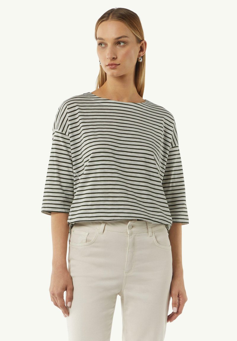 Gestreepte grijs en zwarte T-shirt met korte mouwen, een brede halslijn en een relaxte pasvorm, gecombineerd met lichtgekleurde strakke jeans.