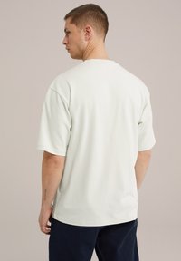 Hele roheline üle mõõtme t-särk, mis on valmistatud pehmest kangast, lühikeste varrukatega ja ümmarguse kaelusega; lihtne disain, ilma nähtavate mustrite või aktsendideta.