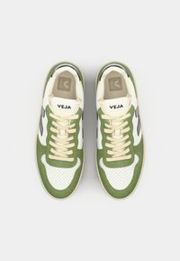 Grønn og hvit sneakers med perforert skinn, beige snøring og svarte detaljer. Har "VEJA"-logo på tungen og siden.