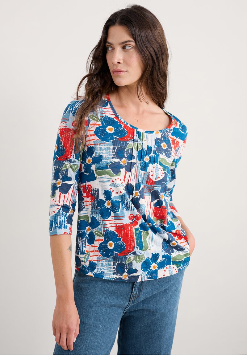 Bluse mit floralem Muster in Blau-, Rot- und Grüntönen. Mit Rundhalsausschnitt und Dreiviertelärmeln. Aus leichtem Stoff gefertigt.