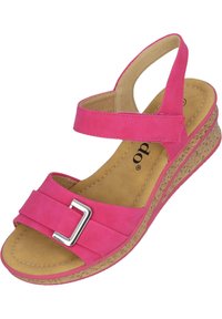 Różowe sandały na koturnie z dwiema paskami, z których jeden ma kwadratową metalową klamrę. Teksturowana podeszwa przypominająca korek zapewnia przyczepność i komfort.