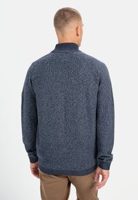 Dunkelblau gestrickter Pullover mit hohem Kragen, strukturiertem Muster und gerippten Bündchen und Saum. Bietet eine lockere Passform mit Raglanärmeln.