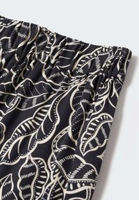 Tissu noir avec un motif abstrait de feuilles blanches, avec une taille élastique froncée.