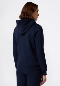Sudadera azul marino hecha de material de felpa suave; cuenta con capucha con cordón y puños y dobladillo acanalados. Diseño simple y clásico.