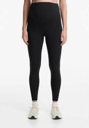 Leggings neri a vita alta realizzati in un tessuto elastico con una texture liscia, caratterizzati da una vita sagomata e un design aderente.
