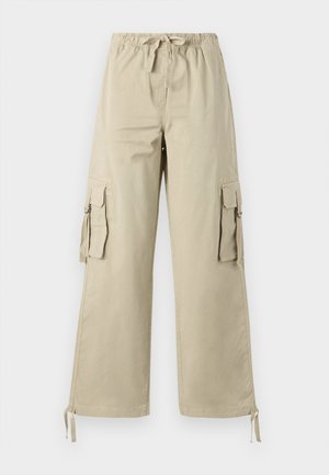 Beige cargo pants with an elastic waistband, drawstring detail, and multiple side pockets. Wide-leg shape and smooth cotton fabric.