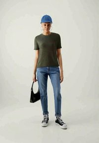 Vihreä lyhythihainen neulepaita, sininen lippalakki, siniset farkut, mustat lenkkarit ja pieni musta käsilaukku. Yksinkertainen, rento asu, jossa on minimaalinen yksityiskohtien määrä.