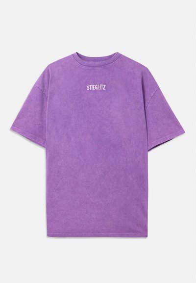 Violeta kokvilnas t-kreklis ar apaļu kakla izgriezumu, īsām piedurknēm un brīvu piegriezumu. Priekšpusē ir balta uzraksts "STIEGLITZ".
