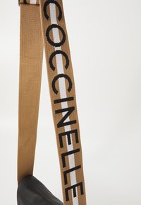 Cintura intrecciata marrone con lettering nero, featuring una striscia bianca. Base in pelle nera texture. Lunghezza regolabile.