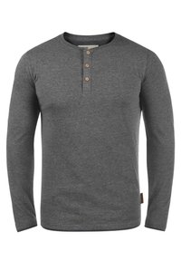 Donkergrijze lange mouwen henley shirt met drie beige knopen op een smalle placket en een klein bruin merklabel aan de zijkant van de onderzoom.
