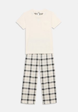 Kokvilnas pidžamas komplekts, kas sastāv no krēmkrāsas īsroku kreklā ar kabatu un melnbaltām pledveida biksēm. Brīva piegriezuma dizains.