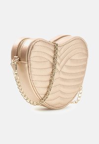 Hartvormige handtas in metallic lichtgoud, gemaakt van getextureerd materiaal met een doorgestikt patroon. Voorzien van een gouden kettingband en ritssluiting.