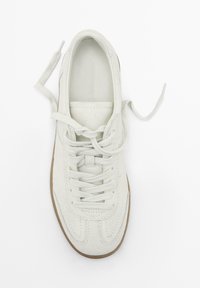 Sneaker in suede bianco con punta rotonda, chiusura con lacci e tomaia texturizzata. Suola in gomma marrone e lacci piatti, con branding minimo sulla soletta.