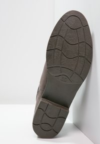 Braune Schuhsohle mit strukturiertem Gummimuster, rechteckigem Absatz und Größenmarkierung "39". Das Material scheint stabil und für eine gute Griffigkeit ausgelegt zu sein.