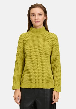 Pull en tricot de couleur vert vif avec un col haut, des poignets côtelés et un motif texturé ; il présente une coupe décontractée et des manches longues.