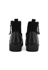 Para czarnych botków za kostkę z ćwiekowanym skórzanym wykończeniem, z uchwytami do zakupu i bocznymi suwakami z dekoracyjnymi koralikami, widziana z tyłu.