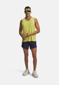 Lime green sleeveless athletic shirt, navy shorts, and white sneakers. The shirt features a loose fit and perforated texture.
