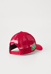 Červená baseballová čiapka s priedušnou zadnou časťou. Má zaoblený okraj, zapínanie na sponu a vyšívaný nápis "TEAM FANTASY" a číslo "22" v zelenej farbe.