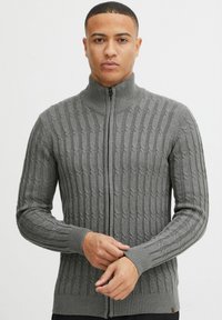 Grauer Reißverschluss-Pullover mit Kabelstrickmuster, geripptem Kragen und Bündchen, tailliertem Schnitt und gewebter Textur.