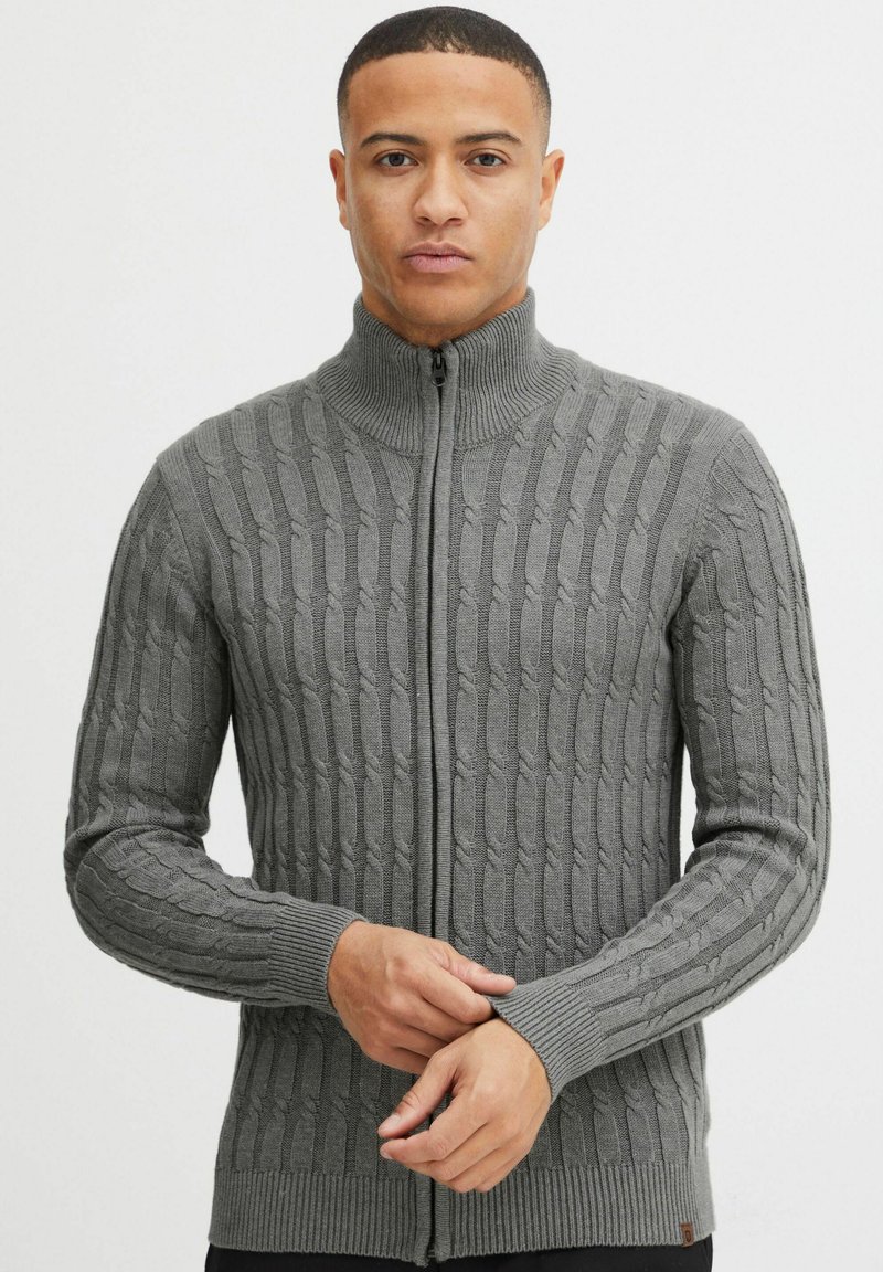 Grauer Reißverschluss-Pullover mit Kabelstrickmuster, geripptem Kragen und Bündchen, tailliertem Schnitt und gewebter Textur.