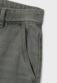 Graue Denim-Hose mit einem subtilen strukturierten Muster, ausgestattet mit einem geraden Taillenbund, seitlichen Taschen und sichtbaren Steppnähten.