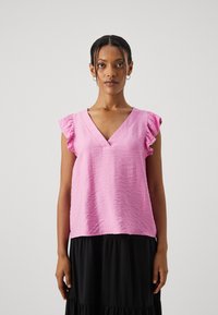Blusa di tessuto arricciato rosa con scollatura a V e maniche a farfalla arricciolate, abbinata a una gonna nera a strati. Texture liscia, vestibilità comoda.
