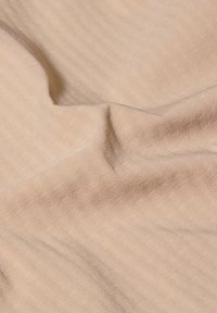 Beiger Stoff mit weicher Textur, der zarte Streifenmuster aufweist. Das Material wirkt leicht und fällt sanft.