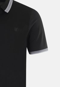 Polo shirt nera a maniche corte, con un tessuto a trama, dettagli a righe grigie sul colletto e un piccolo logo sul petto.