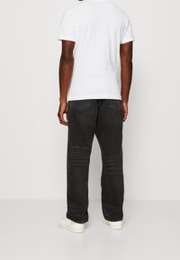 Svarta denimjeans med avslappnad passform, som har två bakfickor och subtila blekningar. Tillsammans med en enkel vit t-shirt med kort ärm och vita sneakers.