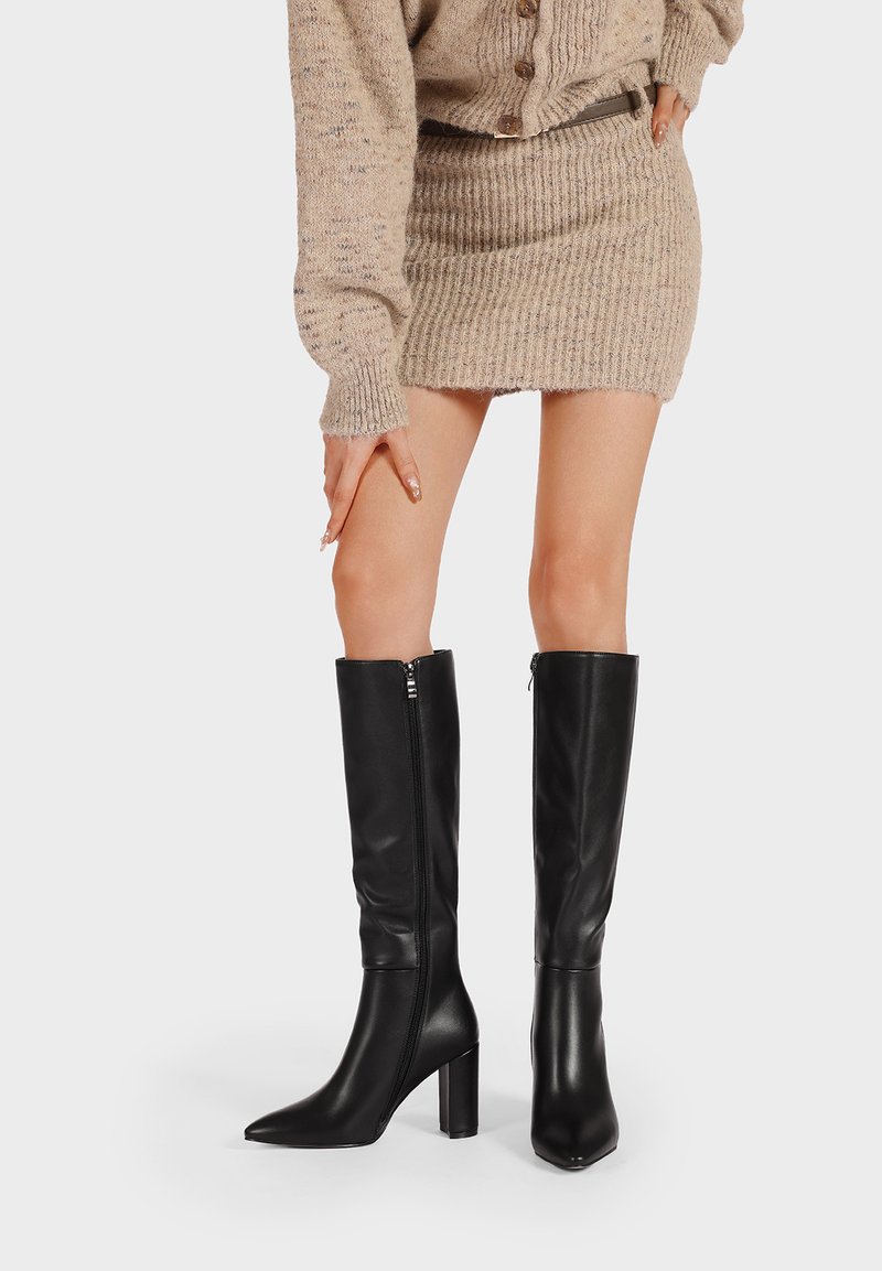 Botas de cuero negras hasta la rodilla con punta afilada y tacón cuadrado, que cuentan con una cremallera lateral y un acabado suave y brillante.