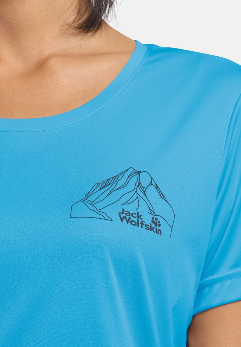 Chemise bleu clair à manches courtes avec un motif de montagne noir et le logo "Jack Wolfskin" sur la poitrine. Tissu synthétique lisse.