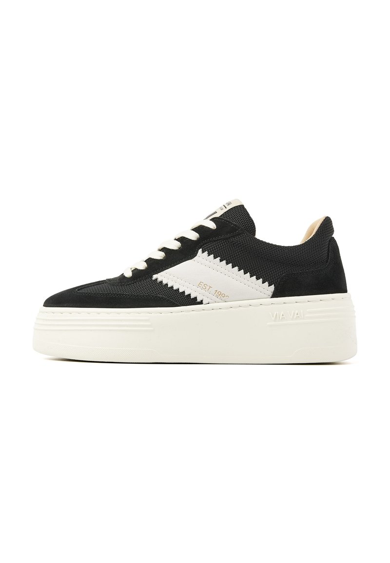 Black sneaker with white accents, textured fabric upper, round toe, and a thick white platform sole. Features prominent zigzag pattern on the side.