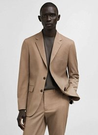 Bež blazer in usklajene hlače s slim fit krojem. Tekstilirana tkanina, en samotni žep na prsih in zapiranje z dvema gumboma. Nosi se preko sivo srajce.