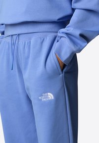 Helleblaue Sweatpants aus weichem Material, mit elastischem Taillenbund, Seitentaschen und gesticktem Logo auf dem linken Oberschenkel.
