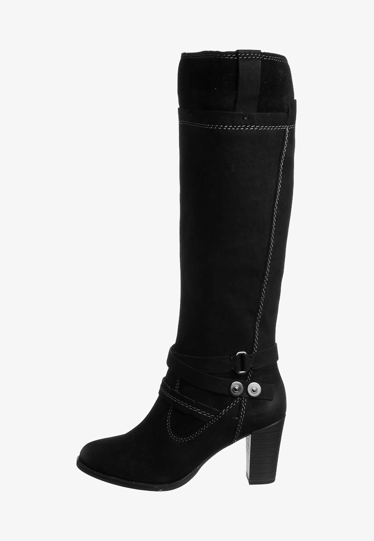 Bota negra hasta la rodilla con textura de ante, que presenta una correa curva con detalles metálicos, un tacón cuadrado y costuras blancas en contraste.