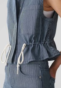 Top senza maniche a righe in tessuto blu scuro e bianco, con orlo a peplum, dettaglio con cordoncino e tasca laterale. Materiale in cotone testurizzato.