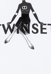 White shirt featuring a black graphic illustration of a figure with a tutu, alongside the text "TWINSET" in bold black letters.