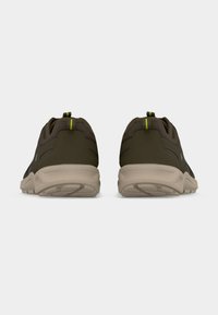 Ζευγάρι σκούρα πράσινα αθλητικά παπούτσια, εμφανιζόμενα από πίσω με ανοιχτομπεζ σόλες και κίτρινες ρίγες στα λουράκια έλξης, σε λευκό φόντο.