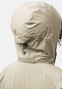 Lichtbeige waterdichte hoodie-jack met een soepele textuur en een verstelbare achterkant. Heeft een eenvoudig ontwerp en geen opvallende hardware.