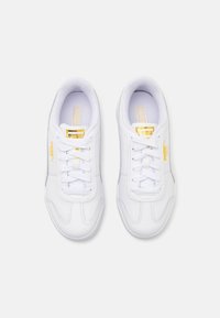 Paire de baskets blanches Puma avec des éléments dorés sur le logo, lacets noués, vue de dessus sur un fond blanc uni.