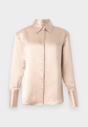 Satinbluse i mykt beige med klassisk krage, lange ermer, knappestrepping foran og en litt oversized passform. Glatt tekstur, minimal detaljering.