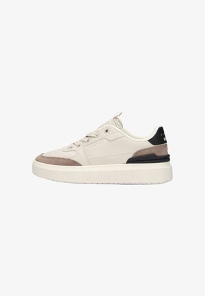 Laagmodel sneaker in beige met suède accenten, zwarte hielstrook en dikke witte zool, zijaanzicht.