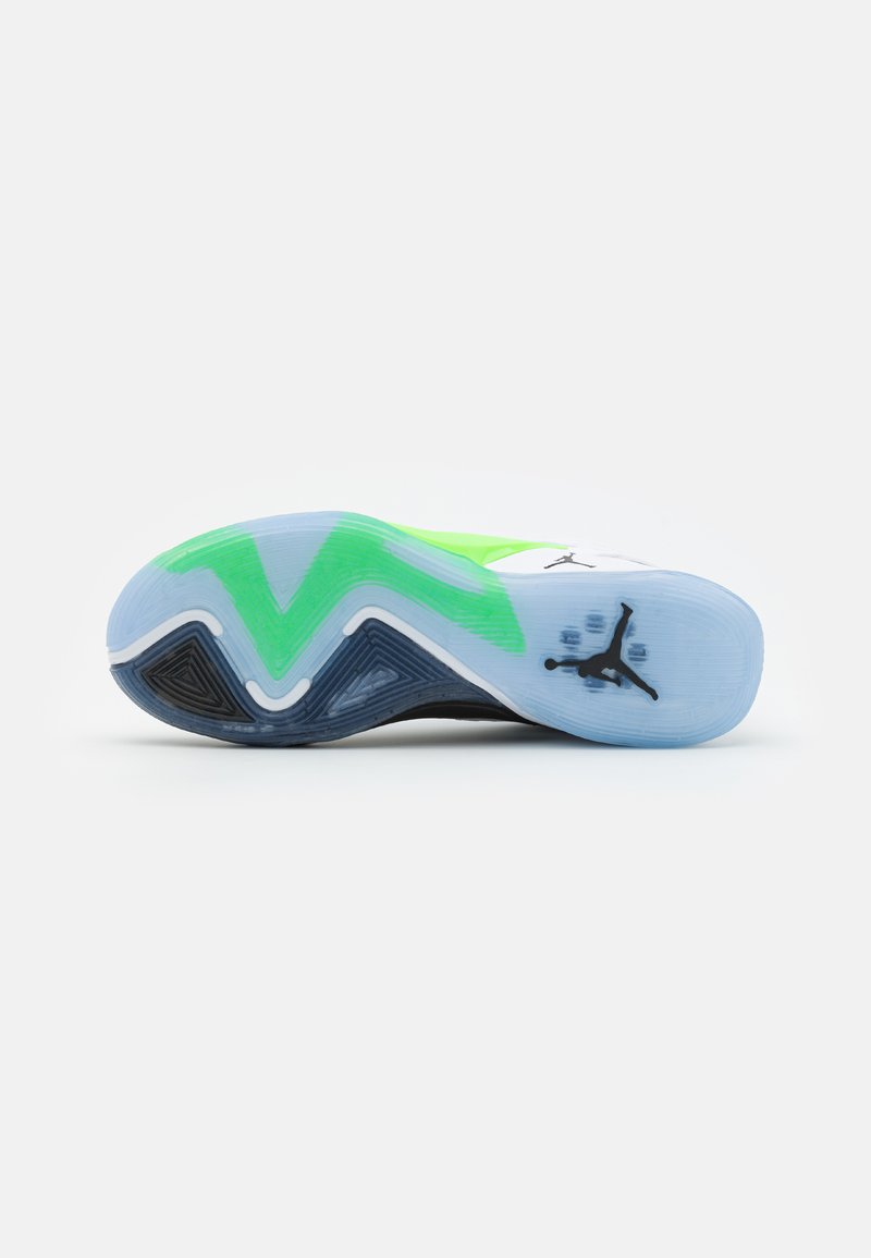 Sole di sneaker con un design ondulato. Predominante bianca con accenti neri e verdi, caratterizzata da una gomma testurizzata e un logo nella zona del tallone.