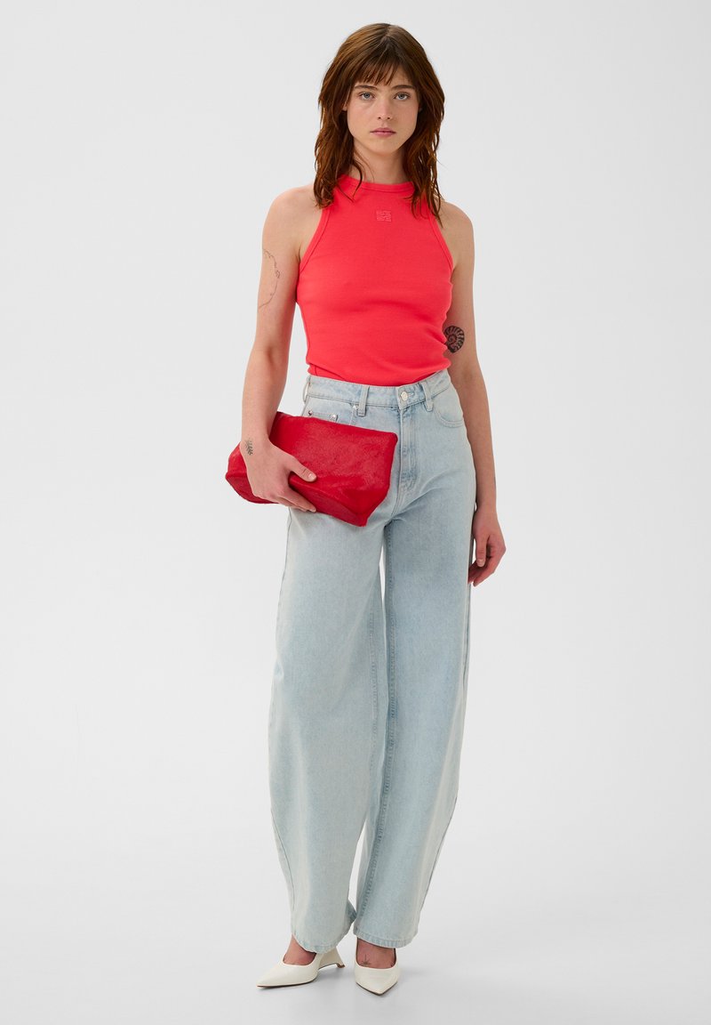 Red halter tank top, light blue high-waisted jeans, white pointed heels, and a red clutch bag. Smooth textures and simple design.