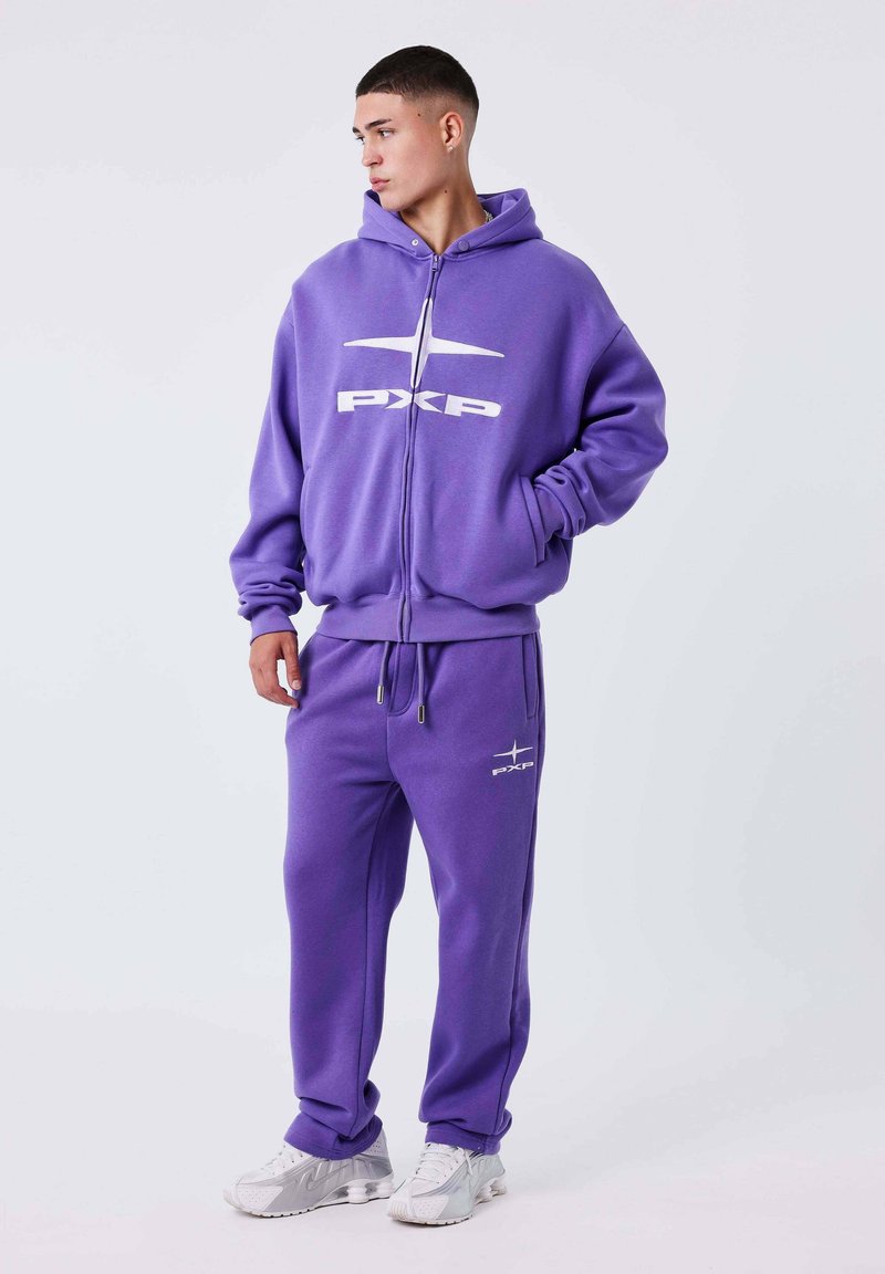Sudadera de cremallera morada con gran logo blanco "PXP", combinada con pantalones jogger morados a juego que presentan un detalle de logo. Tejido suave, corte relajado.