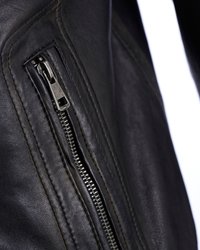 Detail van een zwarte leren jas met een metalen rits, gestructureerd oppervlak en zichtbare stiksels langs de naad nabij de ritssluiting.