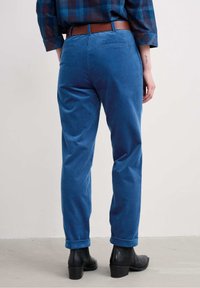 Sinine korduroipükste lõdva istuvusega, millel on rulliääred, kaks tagataskut ja pruun vöö. Kandmiseks mustade ankle'ite saapadega.