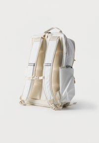 Λευκό αφρώδες σακίδιο με ρυθμιζόμενους ιμάντες, πλαϊνή τσέπη, κλείσιμο με φερμουάρ και άνω λαβή σε απλό λευκό φόντο.