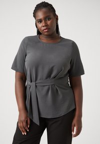Gray short-sleeve top with a fitted bodice and a waist tie. Features a rounded neckline and textured fabric for added detail.