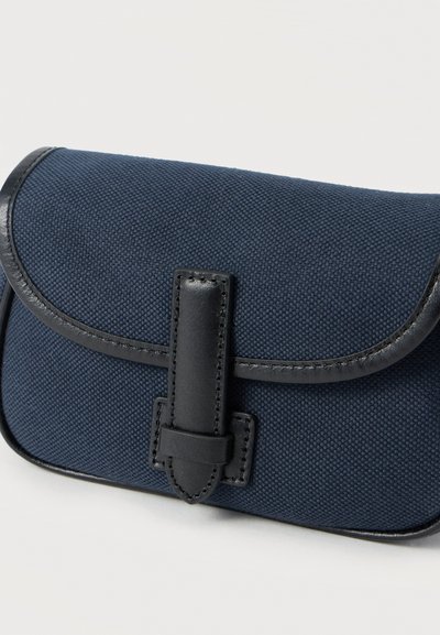 Τσαντάκι από ύφασμα ναυτικού μπλε με καμπυλωτό καπάκι, μαύρες δερμάτινες λεπτομέρειες και υφή με ανάγλυφη επιφάνεια. Διαθέτει κεντρικό λουράκι ως κούμπωμα.